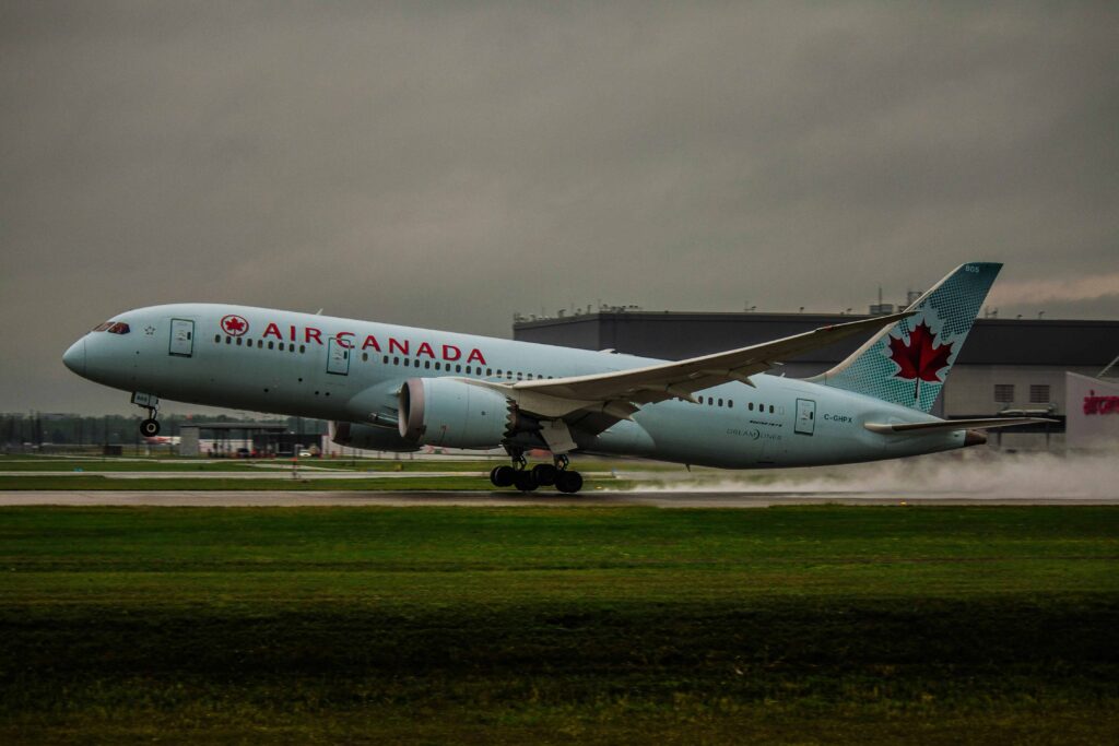 Avião da Air Canada decolando em uma pista úmida com céu nublado, simbolizando as viagens internacionais e a importância da autorização de viagem para menores em voos globais.