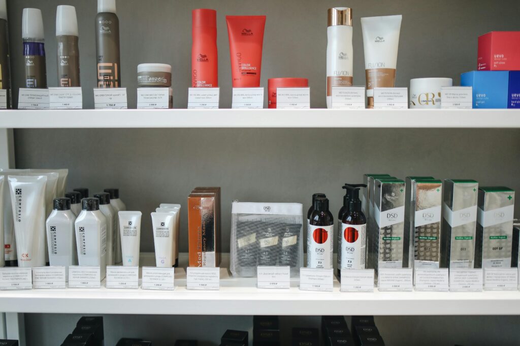 Prateleiras brancas de uma loja exibindo uma variedade de produtos de beleza e cuidados capilares, incluindo shampoos, condicionadores, cremes e tratamentos, de marcas como Wella e DSD, com etiquetas de preço, representando a vasta oferta de cosméticos importados disponíveis para compras no Paraguai.