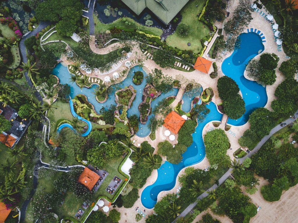 Vista aérea de um resorts de custo-benefício com piscinas em formato de rio, jardins tropicais exuberantes e escorregador aquático, ideal para férias em família.