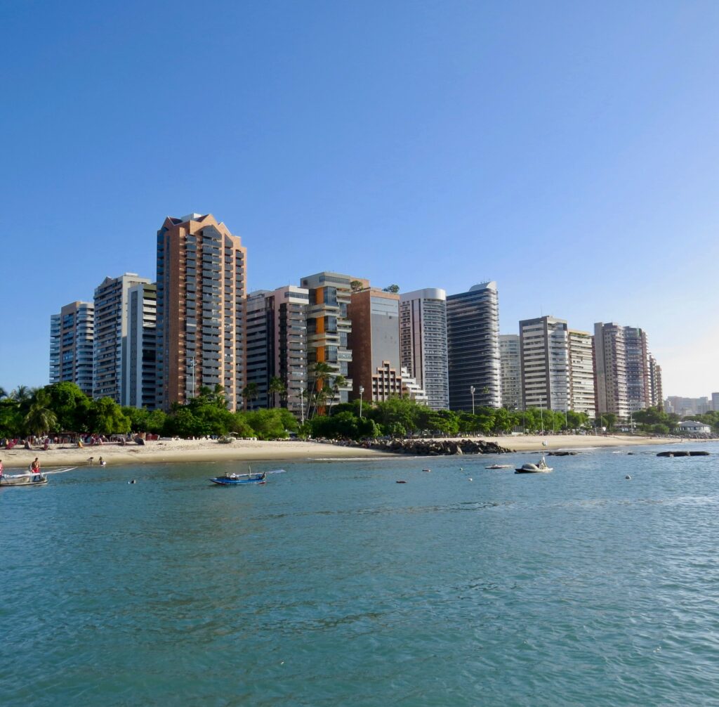 Skyline de Fortaleza visto da água, mostrando prédios altos e modernos na orla de Mucuripe e a Praia de Iracema, Ceará.